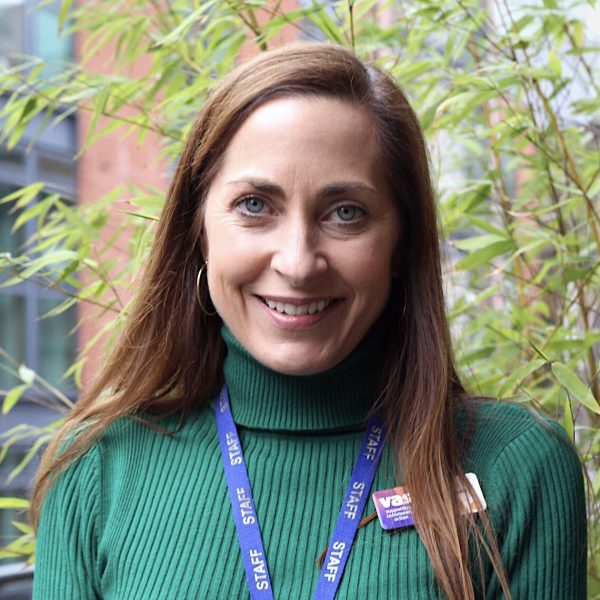 A cheerful woman in a green sweater sports a blue lanyard, radiating positivity and style.