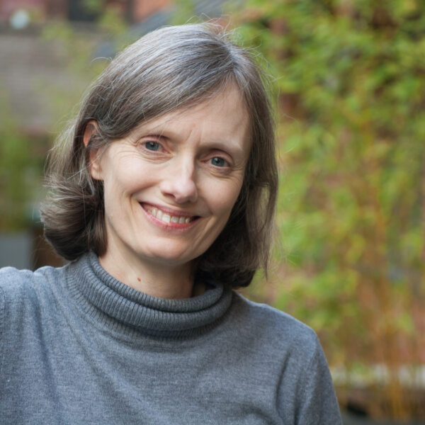 A cheerful woman with gray hair looks directly at the camera, showcasing her joyful expression and friendly demeanor.