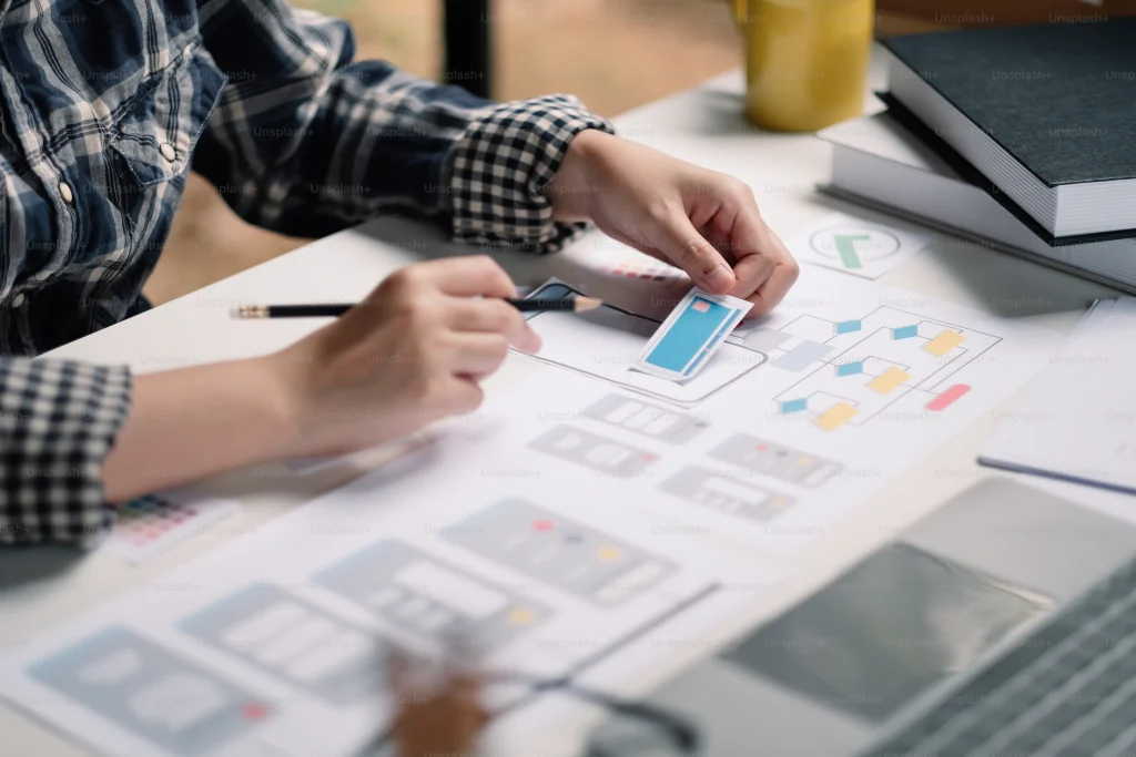 A person typing on a laptop while writing notes with a pen on paper, representing a dynamic workspace.