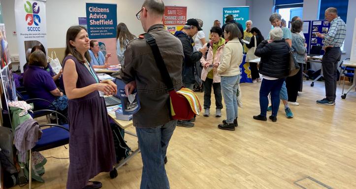 People socializing in a room with tables and chairs, creating a warm and inviting environment for discussion and interaction.